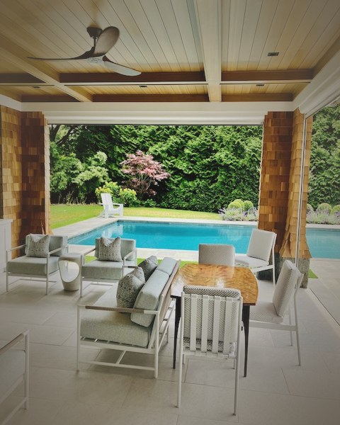 An outdoor poolside cabana with cushioned patio seating